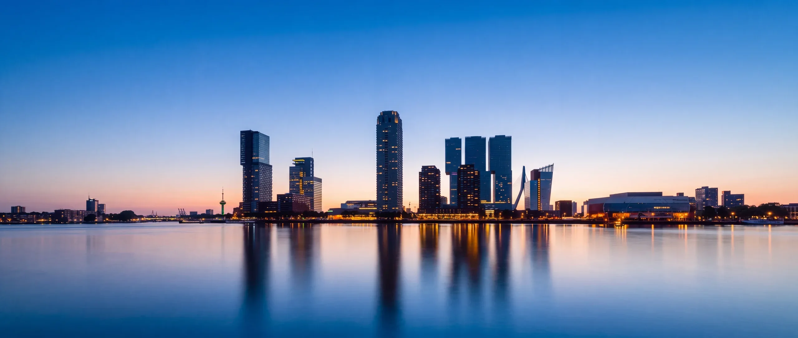 The frontal Kop van Zuid skyline reflected in the River Maas at blue hour, Rotterdam